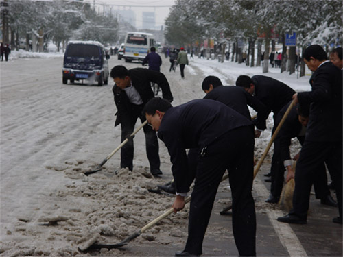 北城支行员工及时清理门前路上积雪,方便行人车辆出行